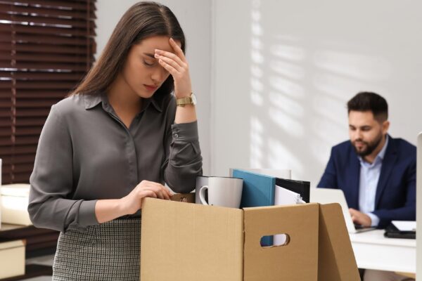 Dismissed woman packing personal stuff into box in office