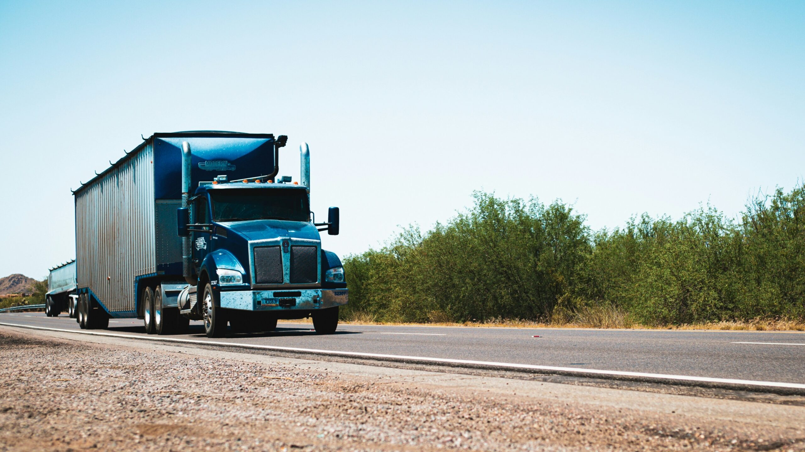 A semi truck driving down the road in the desert