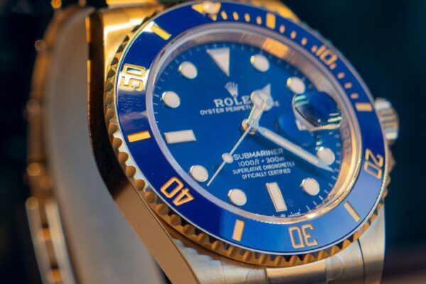 A blue and gold rolex watch on a stand