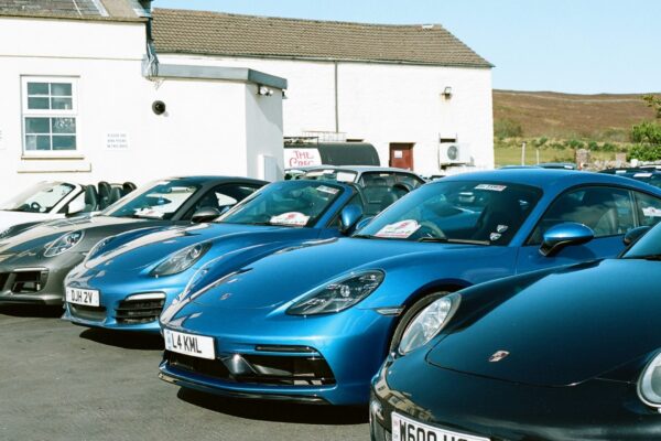 Several blue porsche cars parked in a row.