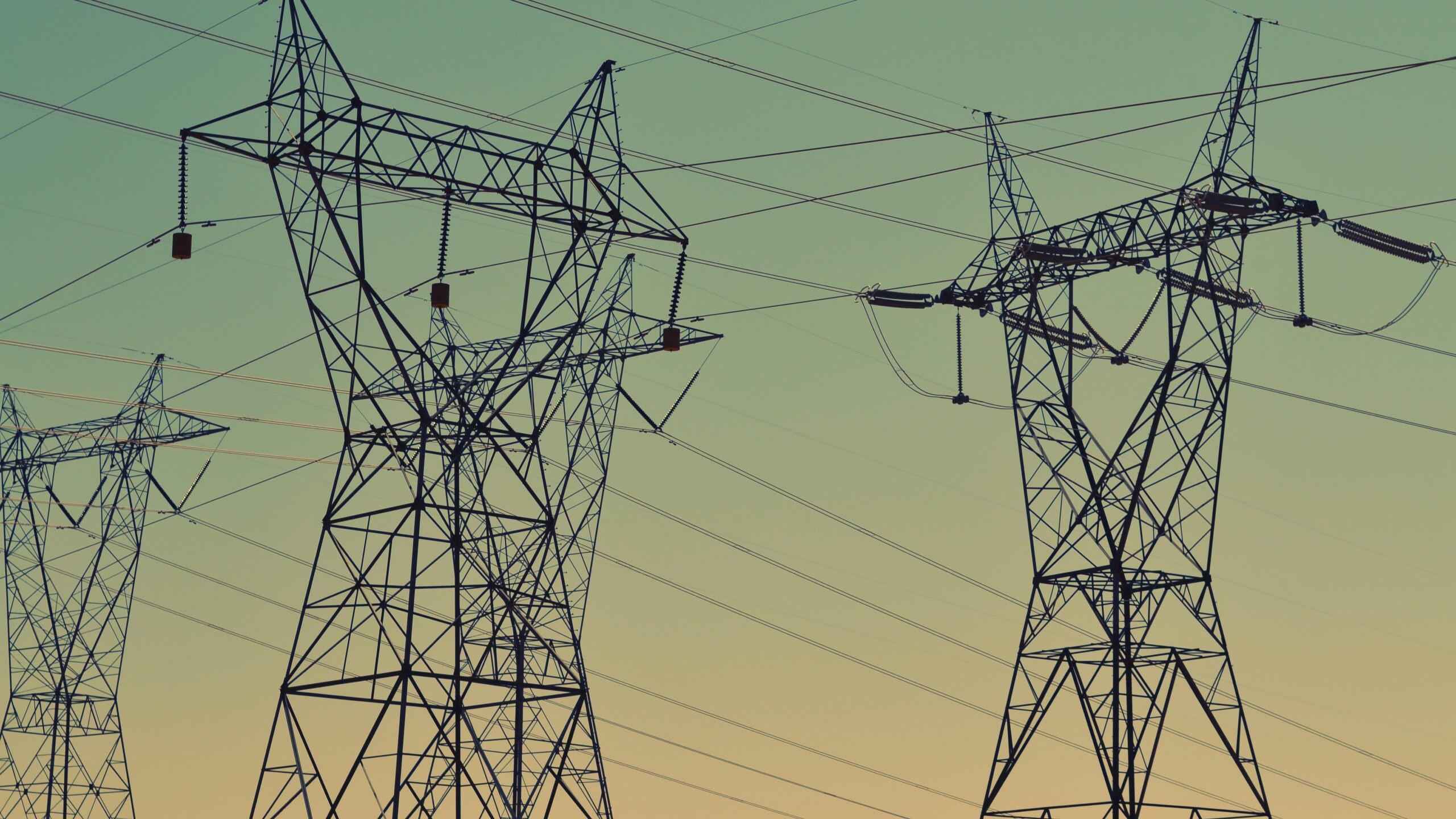 black transmission towers under green sky