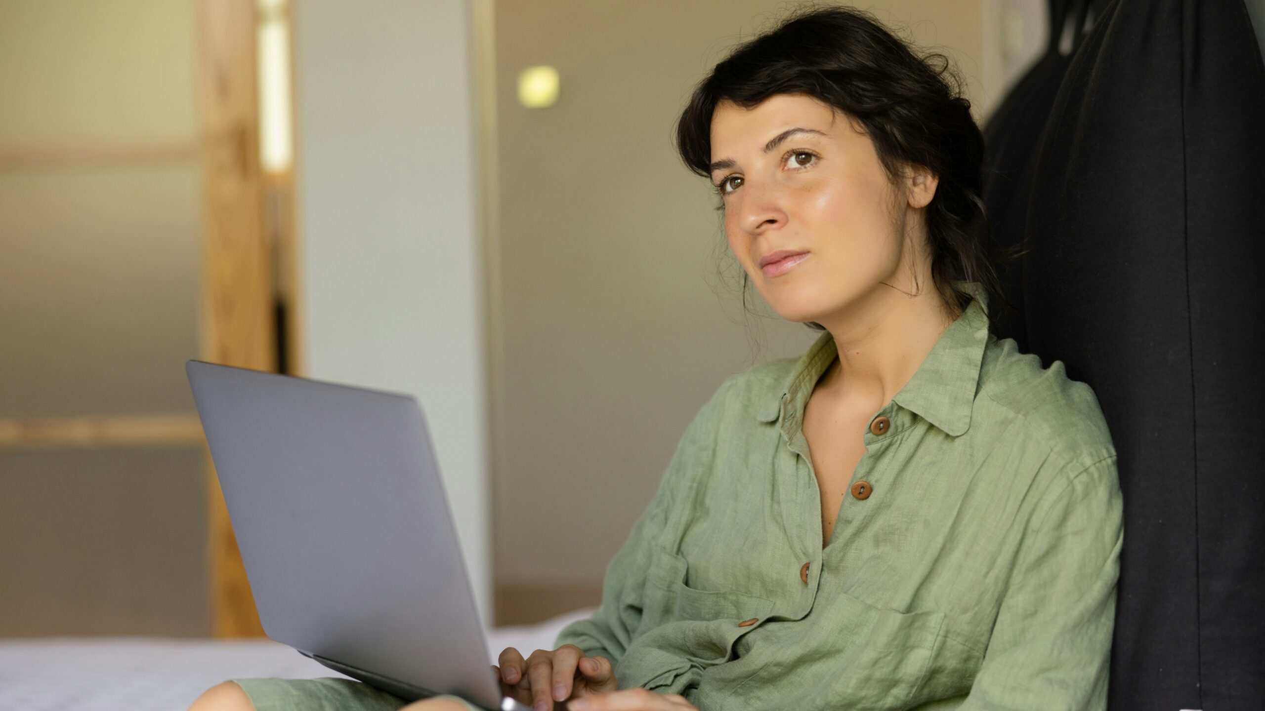 a woman sitting on a bed using a laptop computer