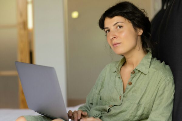 a woman sitting on a bed using a laptop computer