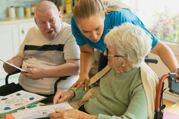 Caregiver assisting elderly couple with coloring