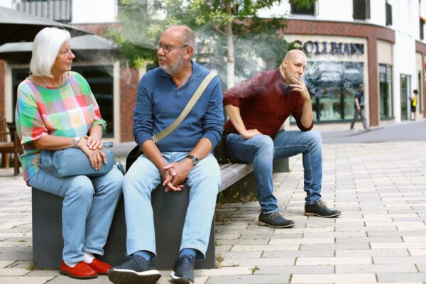 three people sitting on a bench talking to each other