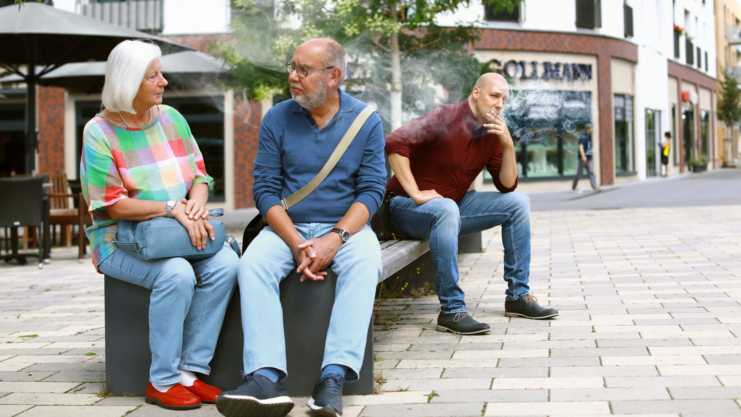 three people sitting on a bench talking to each other