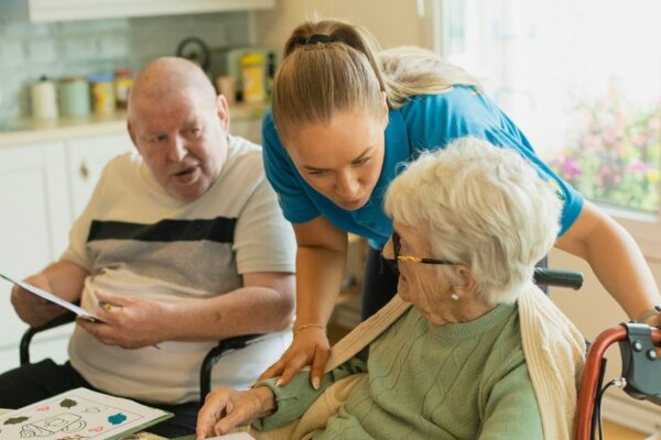 Caregiver assisting elderly couple with coloring