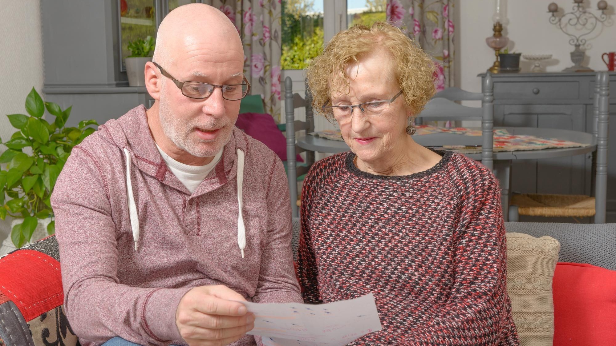 Mature man with woman holding paper on sofa at home