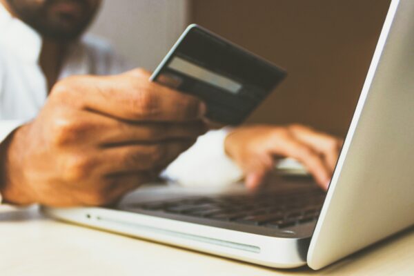 person using laptop computer holding card