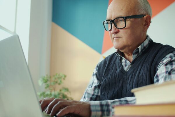 Elderly man with glasses using a laptop
