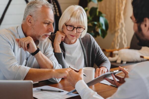 Financial advisor explaining paperwork to elderly retired couple front of desk