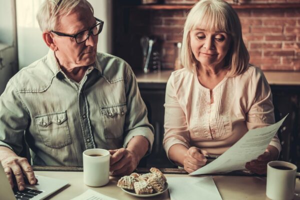 Older couple reviewing documents and using a laptop at home