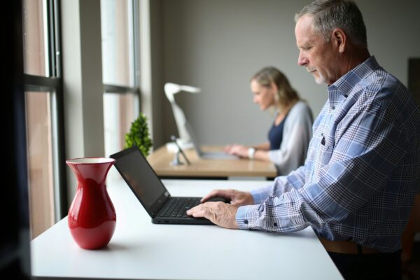 man in blue and white plaid dress shirt using macbook pro