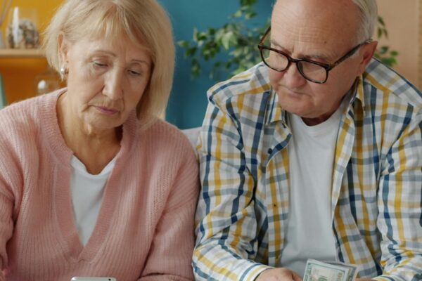 Elderly couple looking at bills and phone