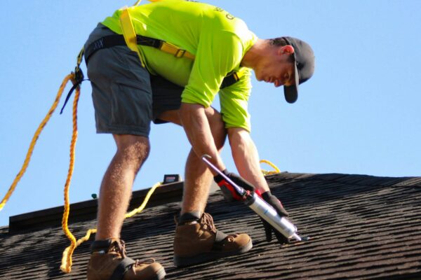 a man in a yellow shirt is working on a roof