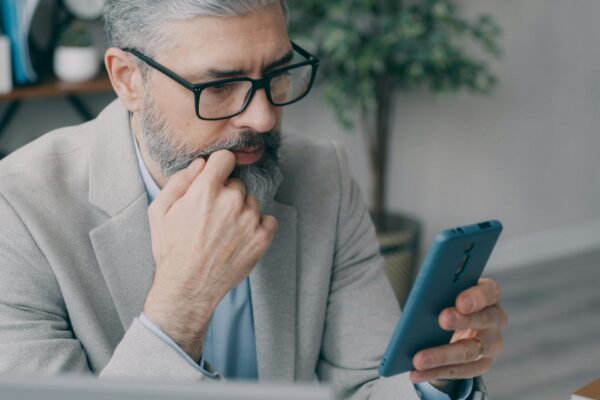 A man sitting at a desk looking at a cell phone
