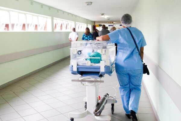 person walking on hallway in blue scrub suit near incubator