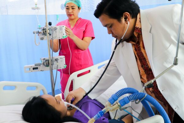 a man laying in a hospital bed being examined by a nurse