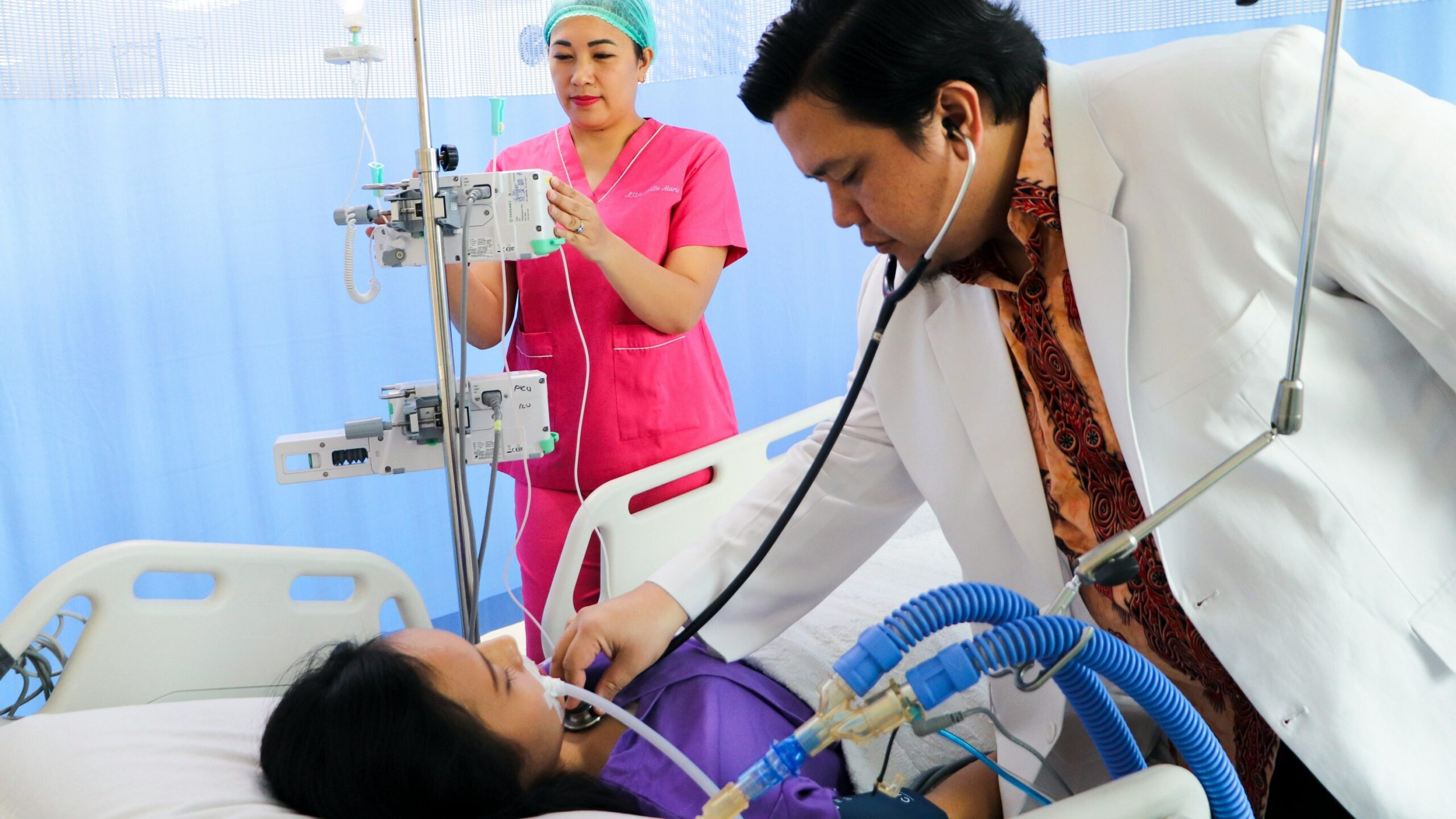 a man laying in a hospital bed being examined by a nurse