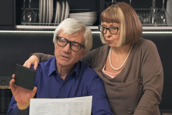 Senior couple calculate their bills on kitchen