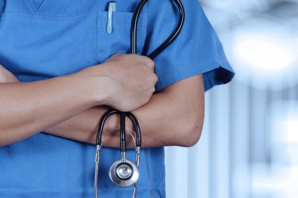 a person in scrubs with a stethoscope on their arm