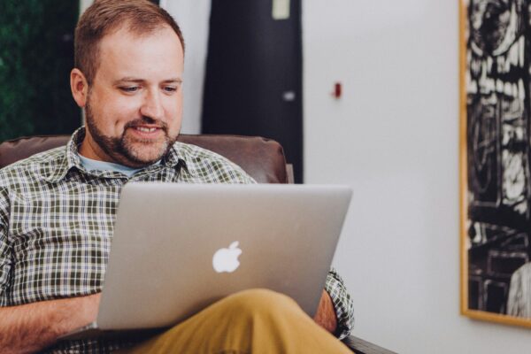 man smiling and using MacBook