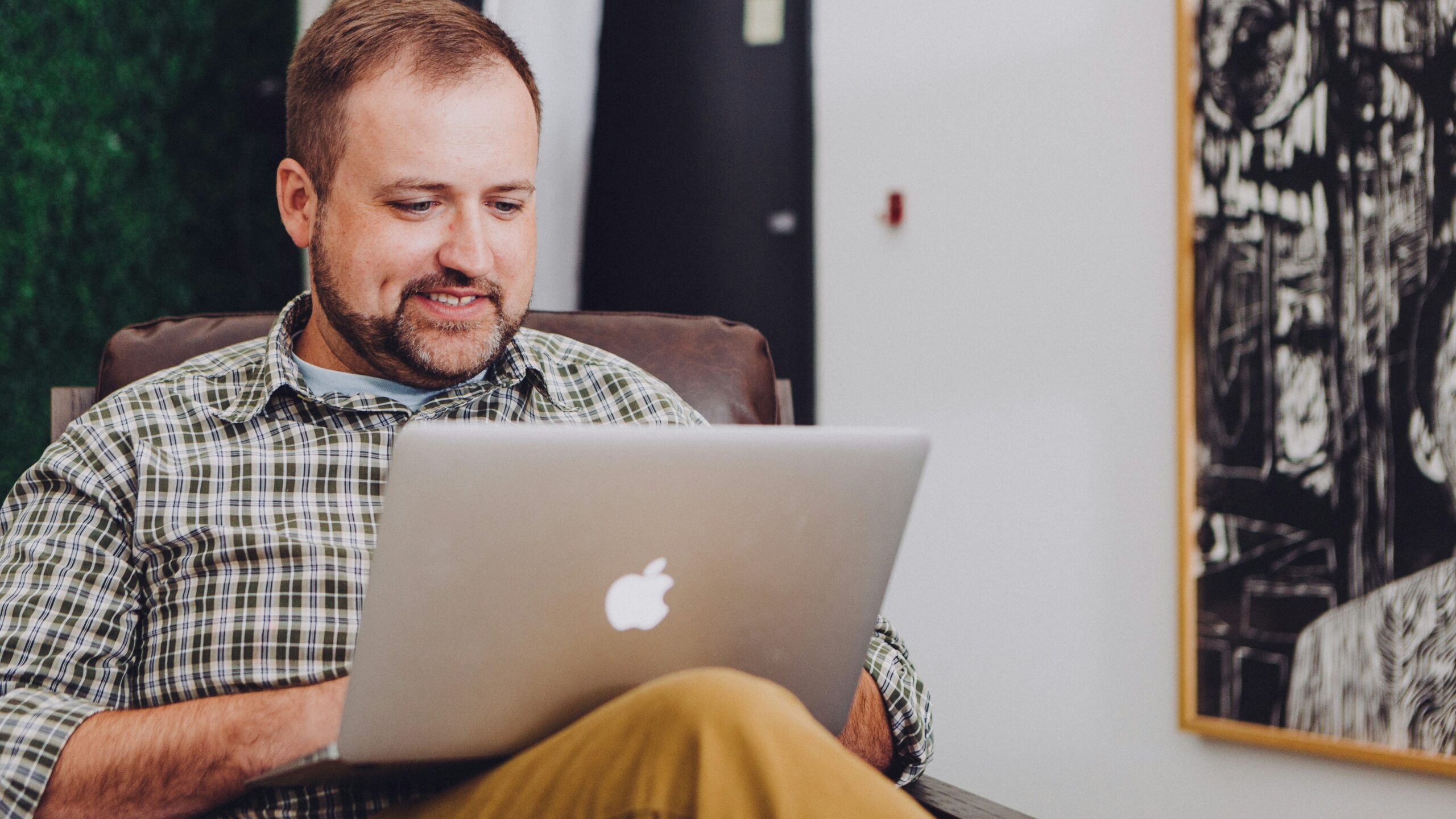 man smiling and using MacBook