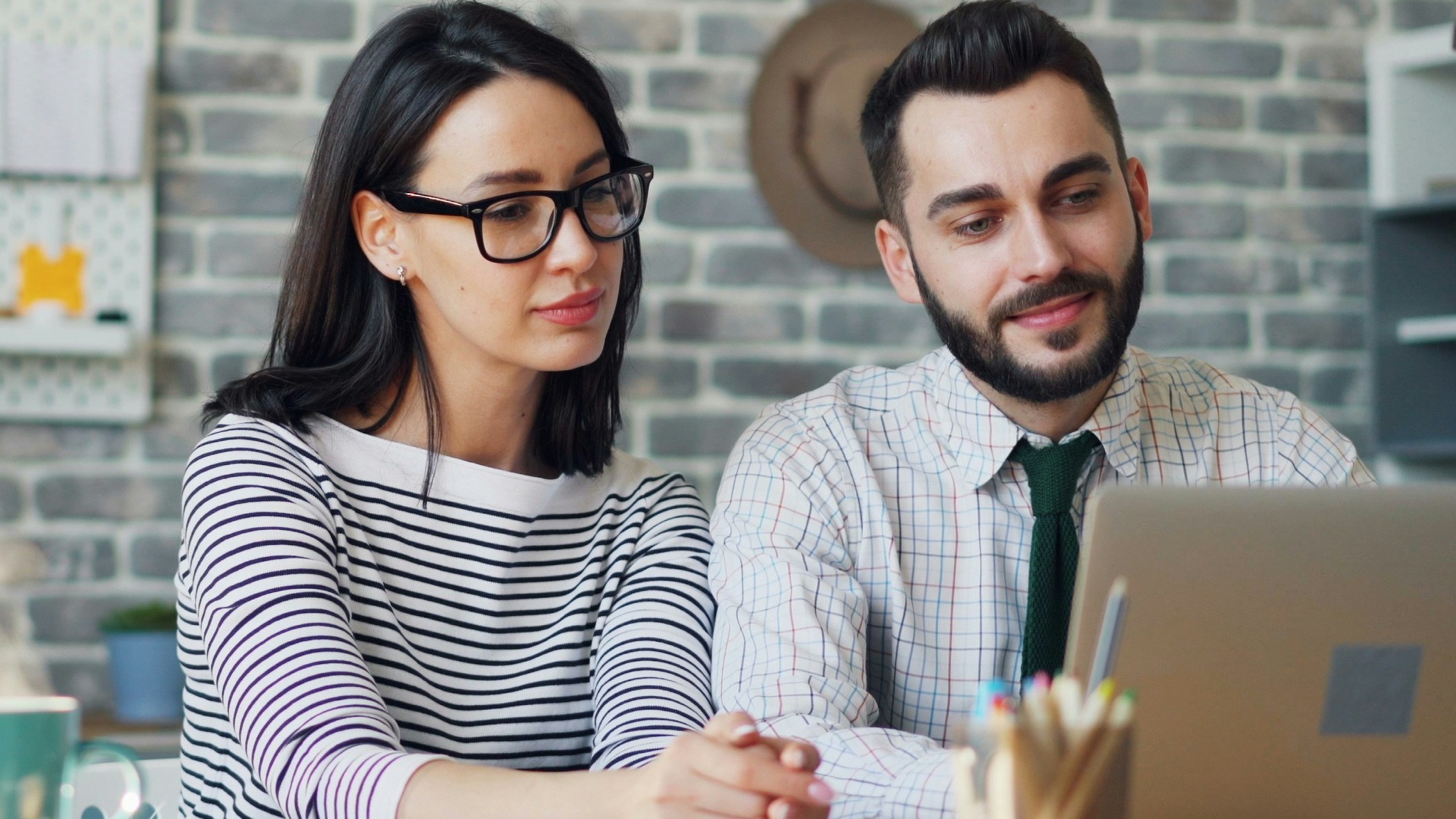 a man and woman sitting at a table looking at a laptop