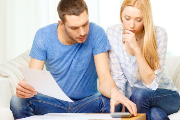 tax, finances, family, home and happiness concept - busy couple with papers and calculator at home