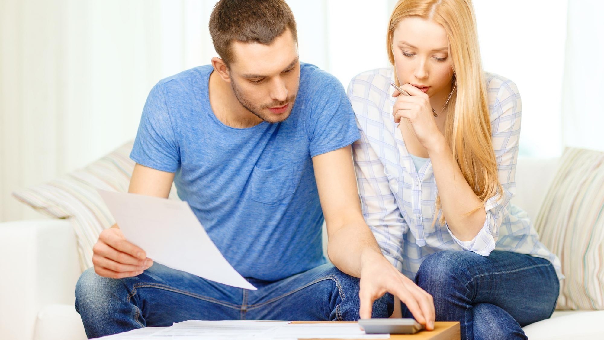 tax, finances, family, home and happiness concept - busy couple with papers and calculator at home