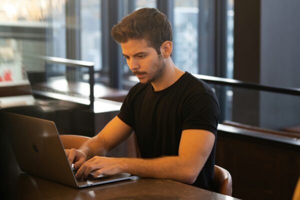 man in black crew neck t-shirt using macbook