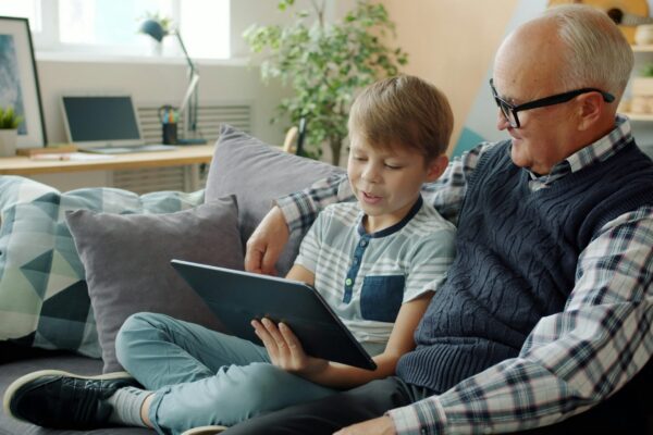 Grandfather and grandson looking at a tablet together.