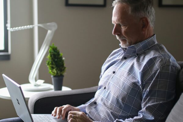 man in blue and white plaid dress shirt sitting on black couch