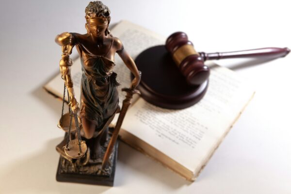 Statue of justice, gavel, and open book on table.