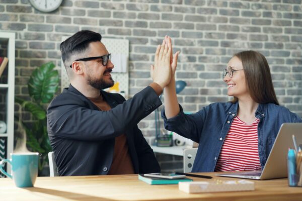 a man and a woman sitting at a table high fiving each other