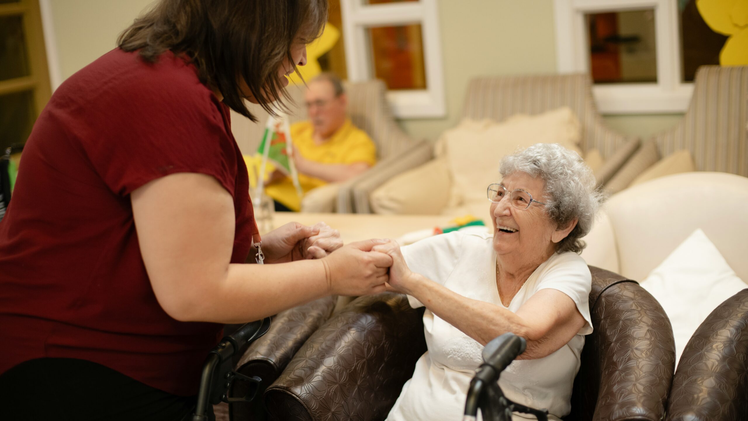 Caregiver assists elderly woman with walker.