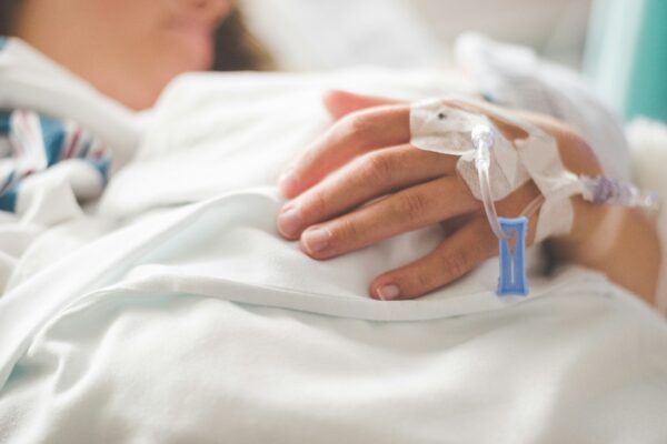a woman laying in a hospital bed with an iv in her hand