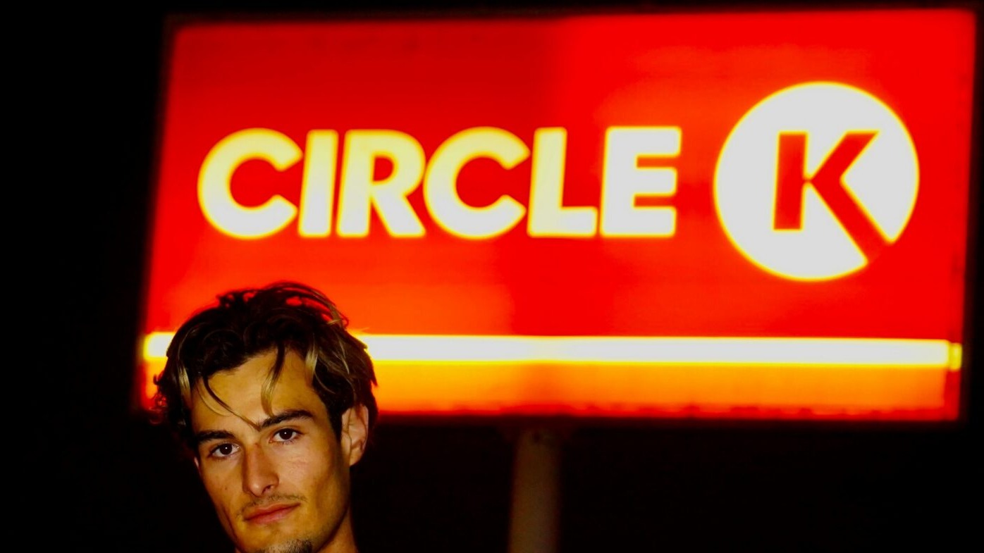 A man standing in front of a circle k sign