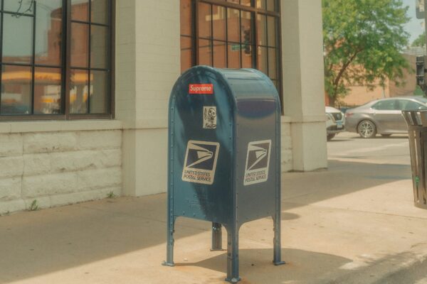 A blue mailbox sitting on the side of a street