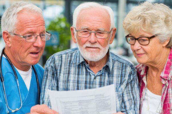 Medical worker showing document to senior couple