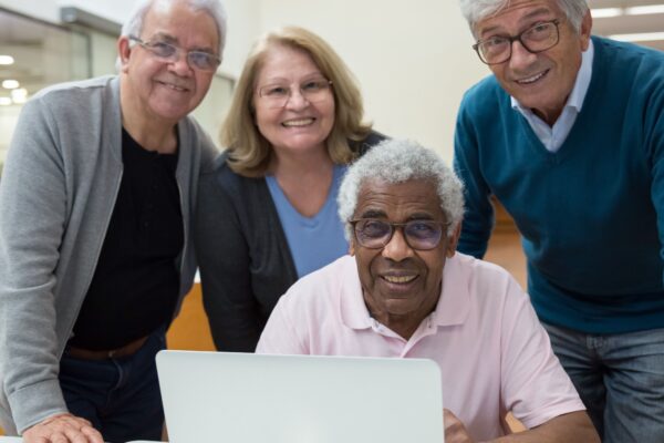 Four senior adults enjoying a computer learning session in a classroom setting.