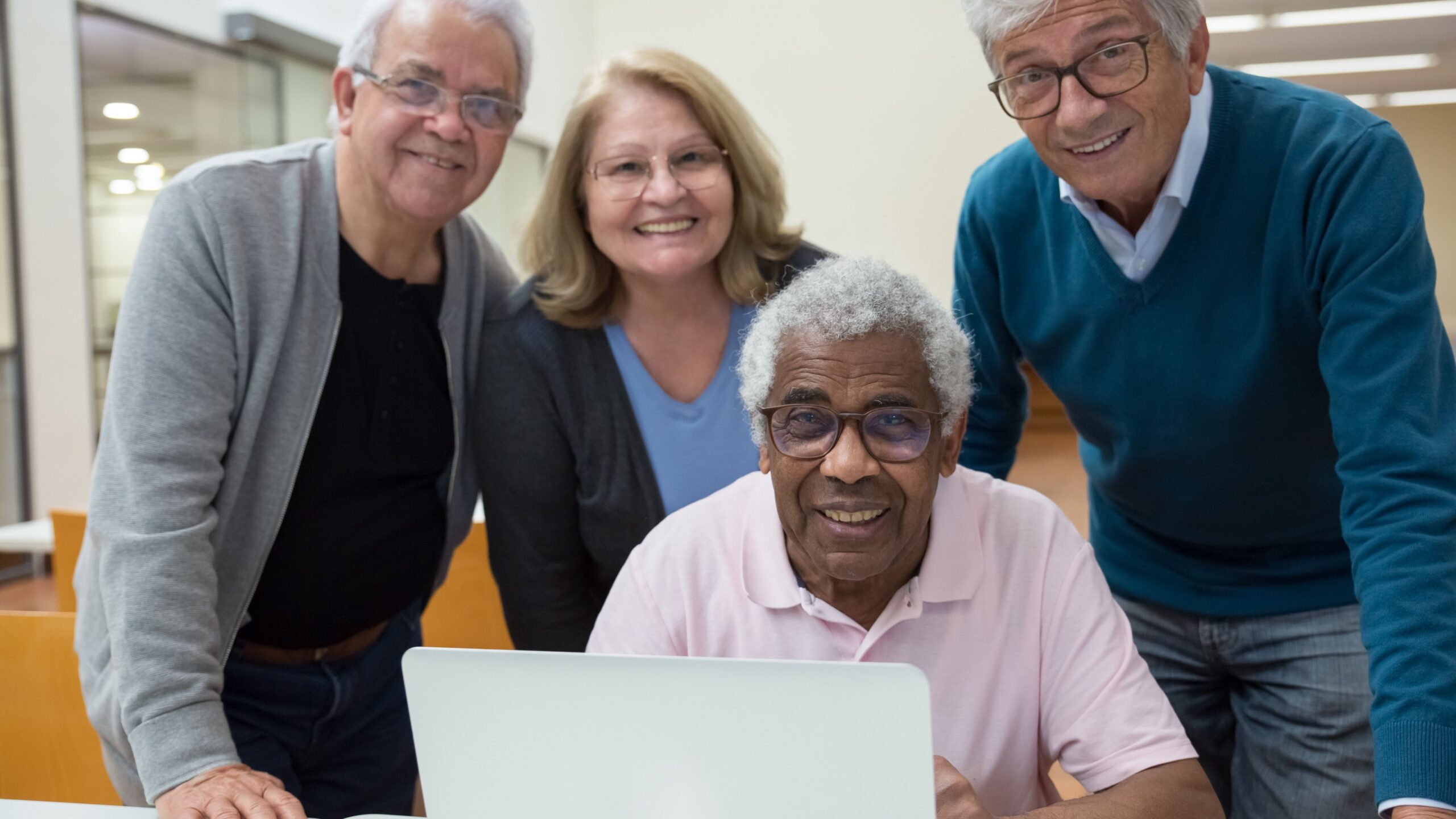Four senior adults enjoying a computer learning session in a classroom setting.