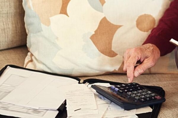 Senior man notebook and calculator on sofa for budget planning and savings account for retirement Elderly person bills and couch in lounge for mortgage personal debt and loan repayment ay home
