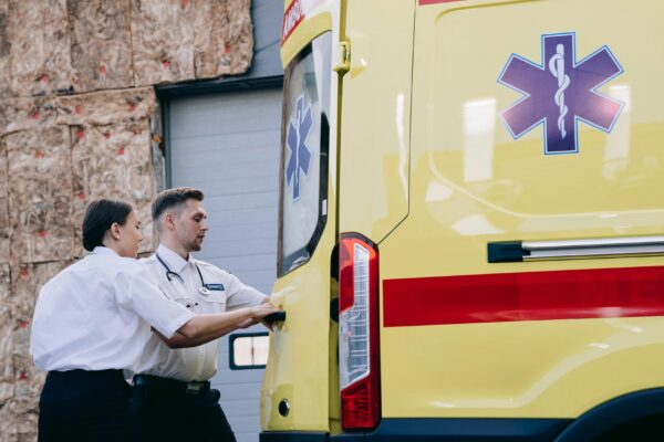 Two paramedics close the rear doors of an ambulance, preparing for emergency response.