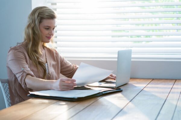 Woman looking at bill while using laptop