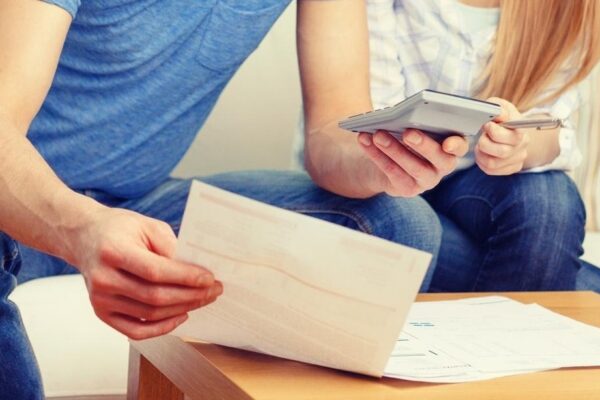 tax, finances, family, home and happiness concept - busy couple with papers and calculator at home