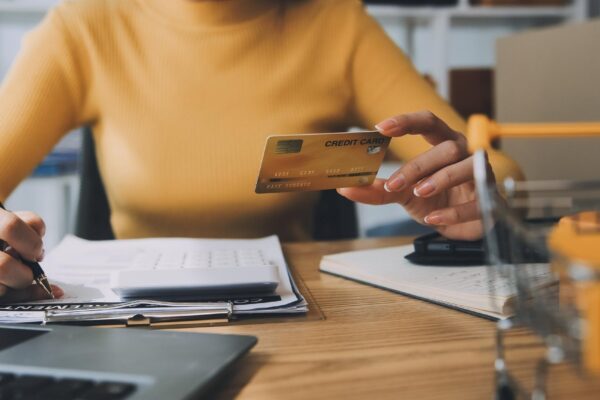 Young woman holding a smartphone tablet showing payment success and credit card with yellow parcel box as online shopping concept in office