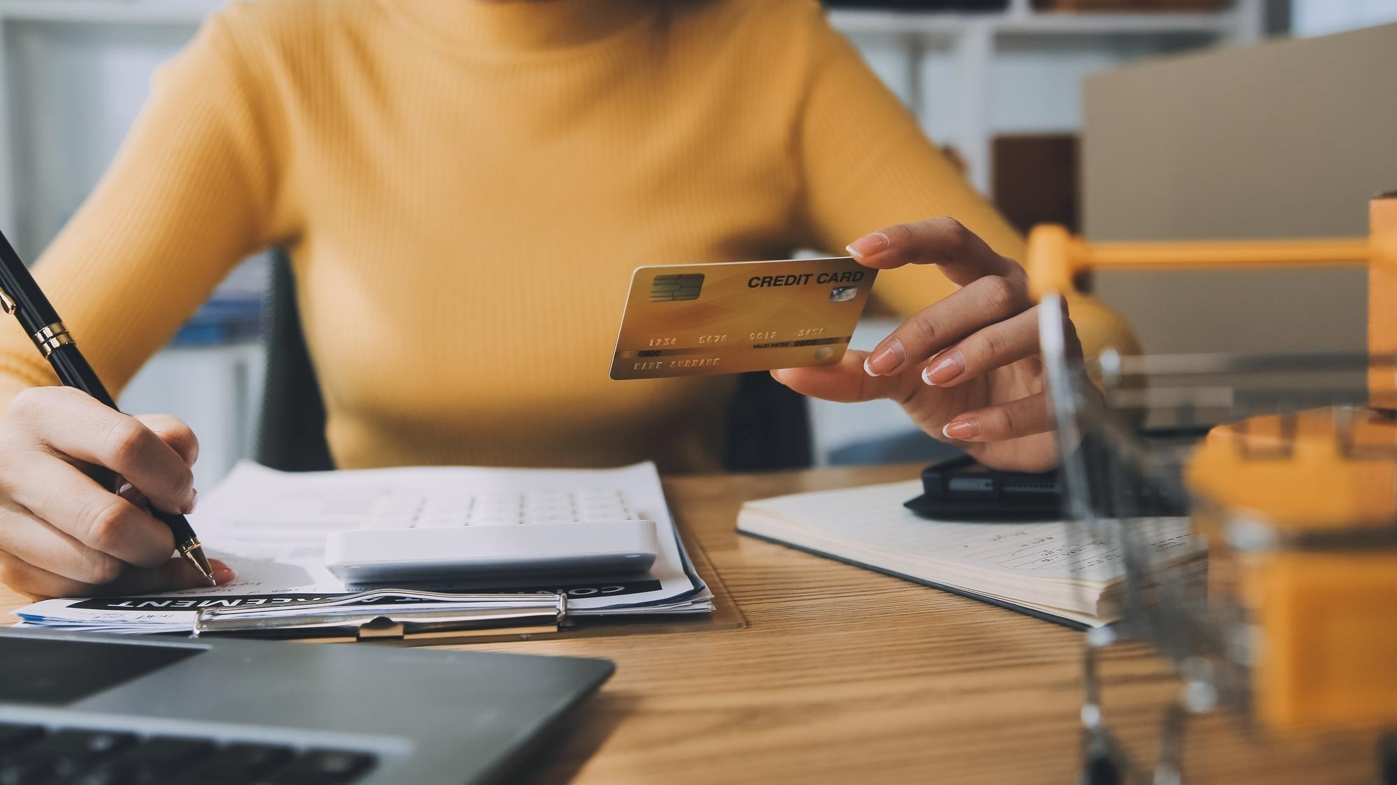 Young woman holding a smartphone tablet showing payment success and credit card with yellow parcel box as online shopping concept in office