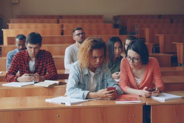 Students looking at phones in a lecture hall.