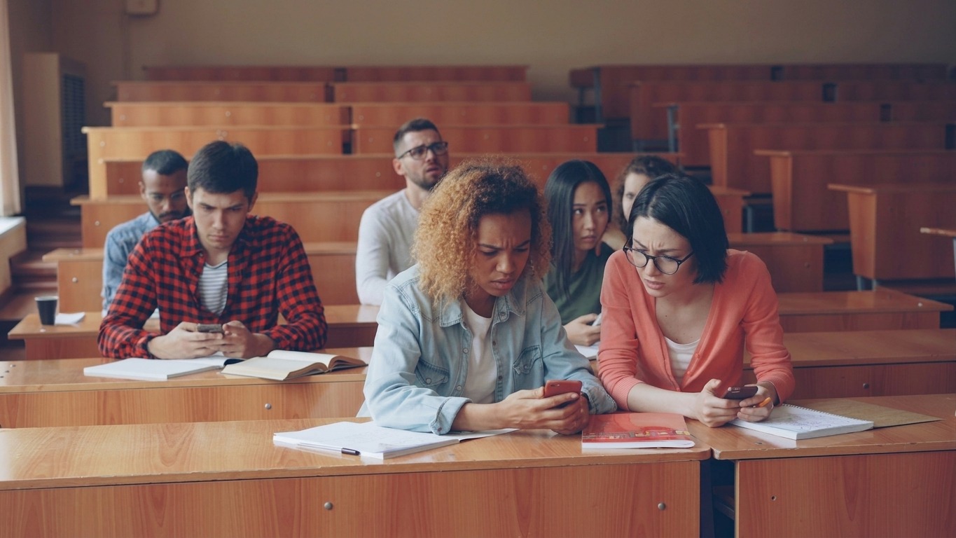 Students looking at phones in a lecture hall.